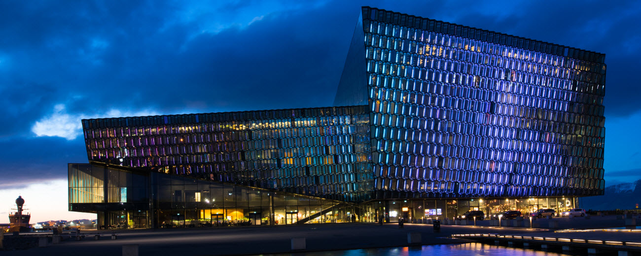 Harpa Concert Hall illuminated beside Reykjavík harbour at blue hour