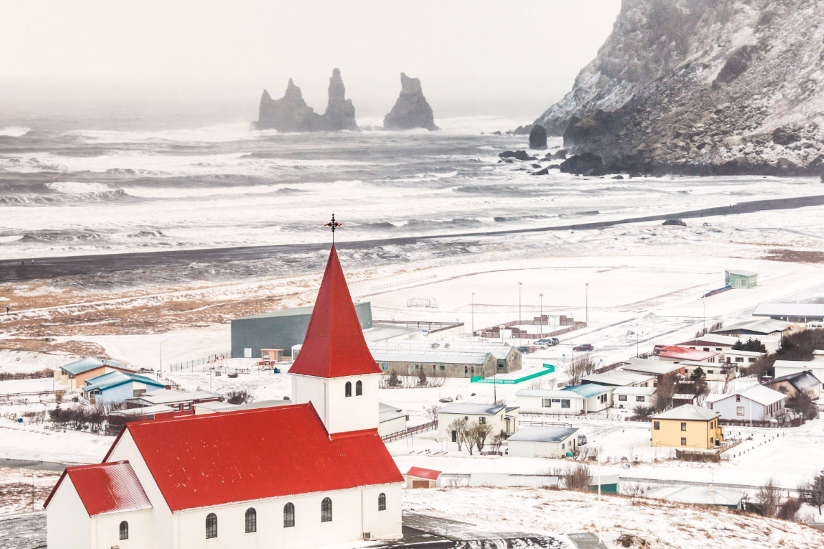 The town Vík during winter with the basalt sea stacks Reynisdrangar in the background