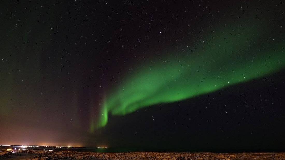 Northern Lights above the sea near Sky Lagoon