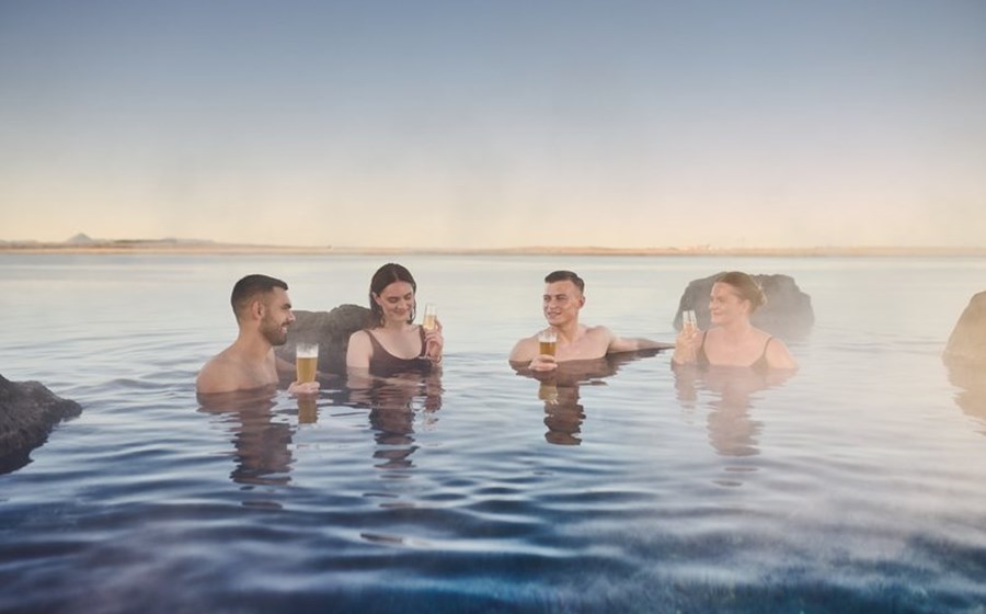 Guests enjoying drinks in the warm lagoon at Sky Lagoon