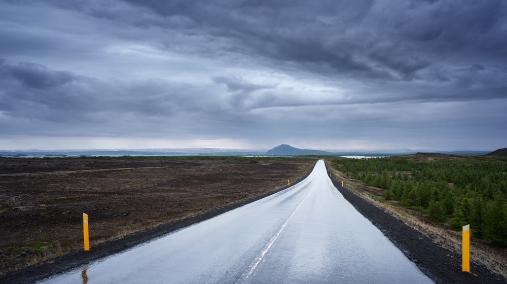 Wet Icelandic road beneath a dark storm near Mývatn