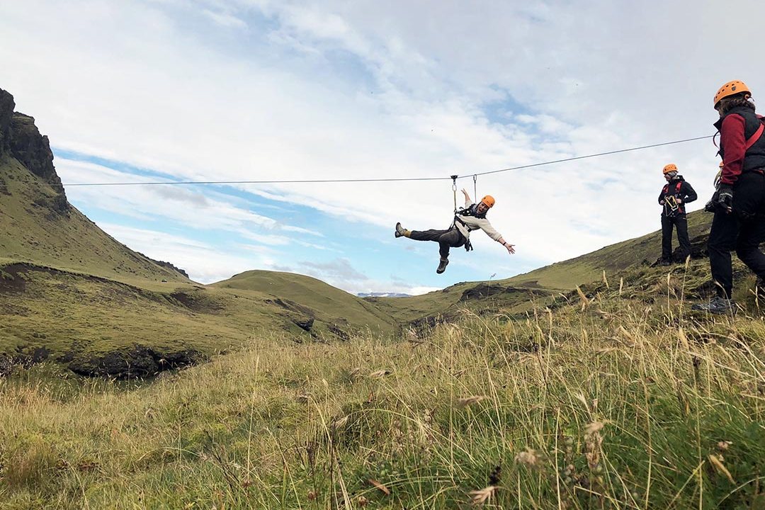 Guest riding a zipline through a green canyon near Vík