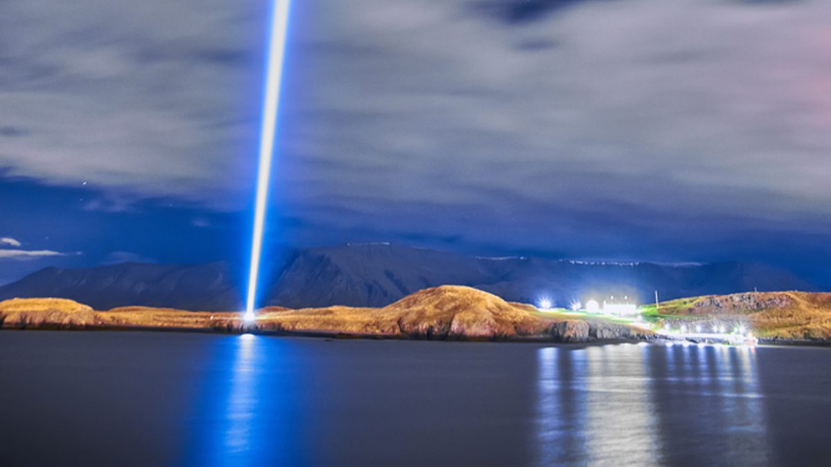 Imagine Peace Tower casting a beam of light above Viðey island at night
