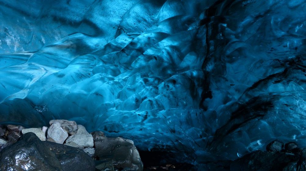 Blue ice cave in Iceland with dark volcanic glacier texture